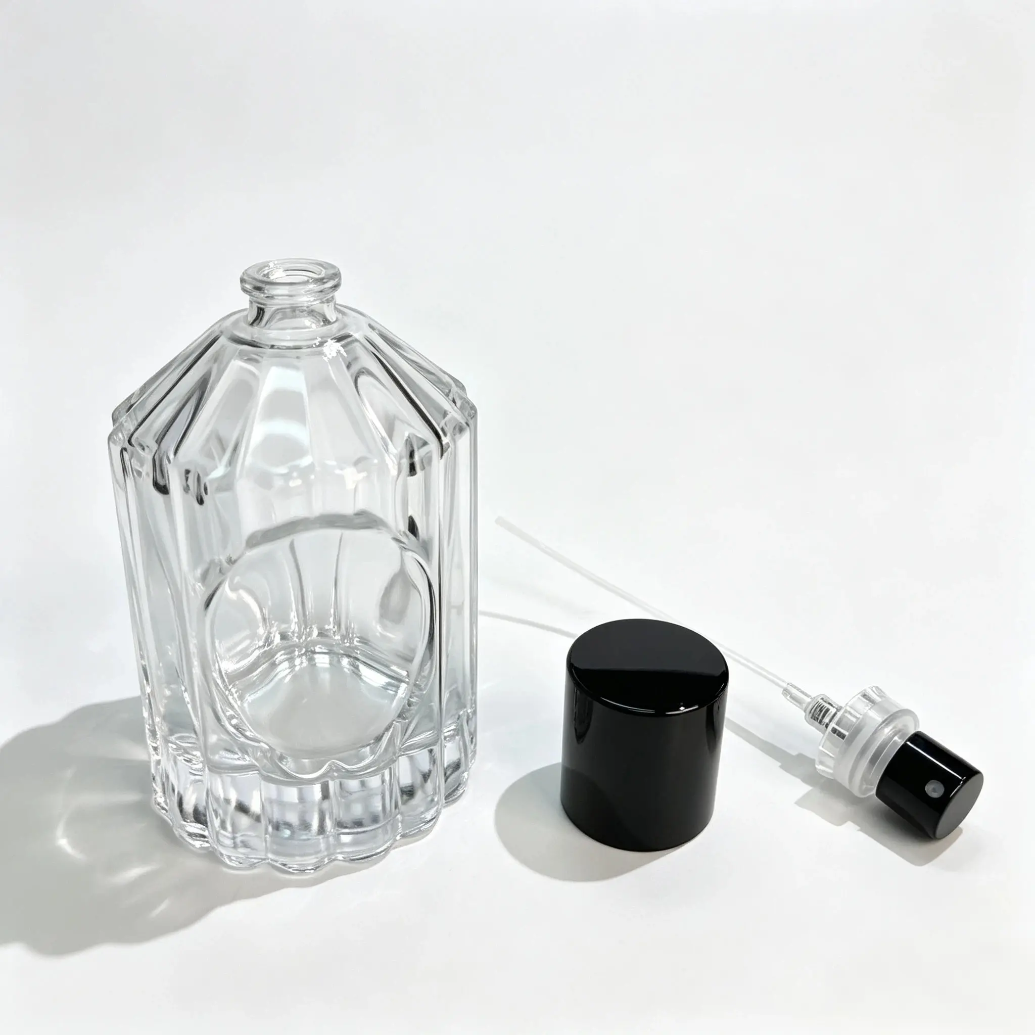 100ml ribbed glass perfume bottle shown with the outer cap and crimp sprayer separated for component reference