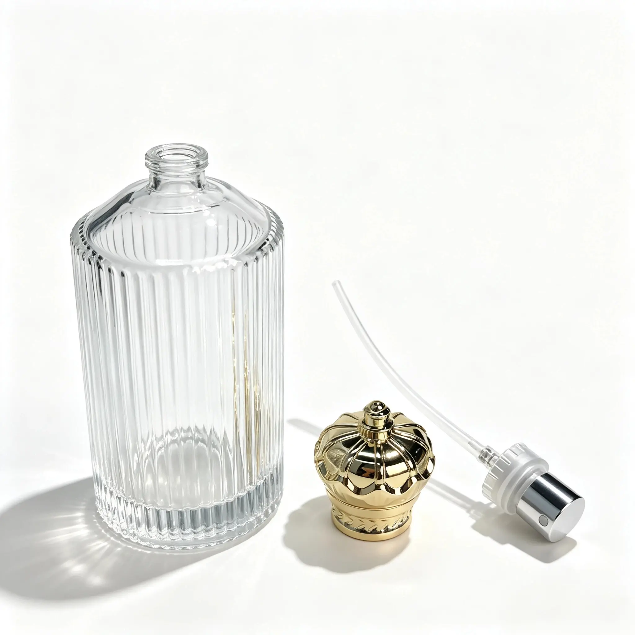 100ml Ribbed Glass Perfume Bottle with Cap and Crimp Sprayer 100ml ribbed glass perfume bottle shown with the gold crown cap and crimp sprayer displayed separately for component review