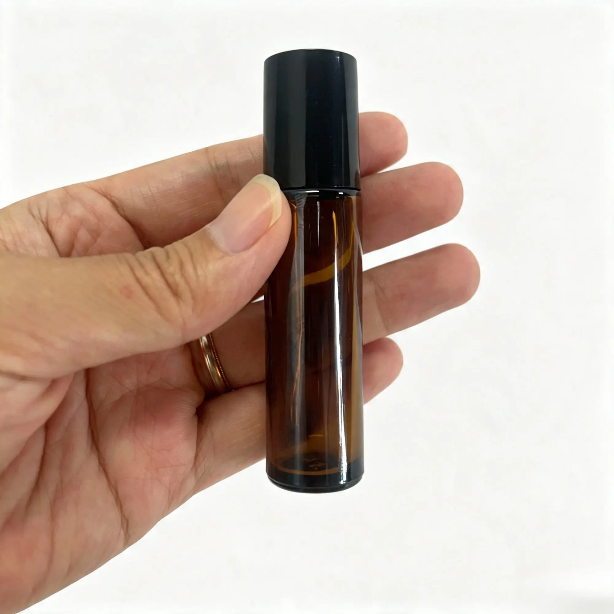 10ml Amber Glass Roller Bottle Handheld View 10ml amber glass roll on perfume bottle held in hand showing the compact proportions of the finished package