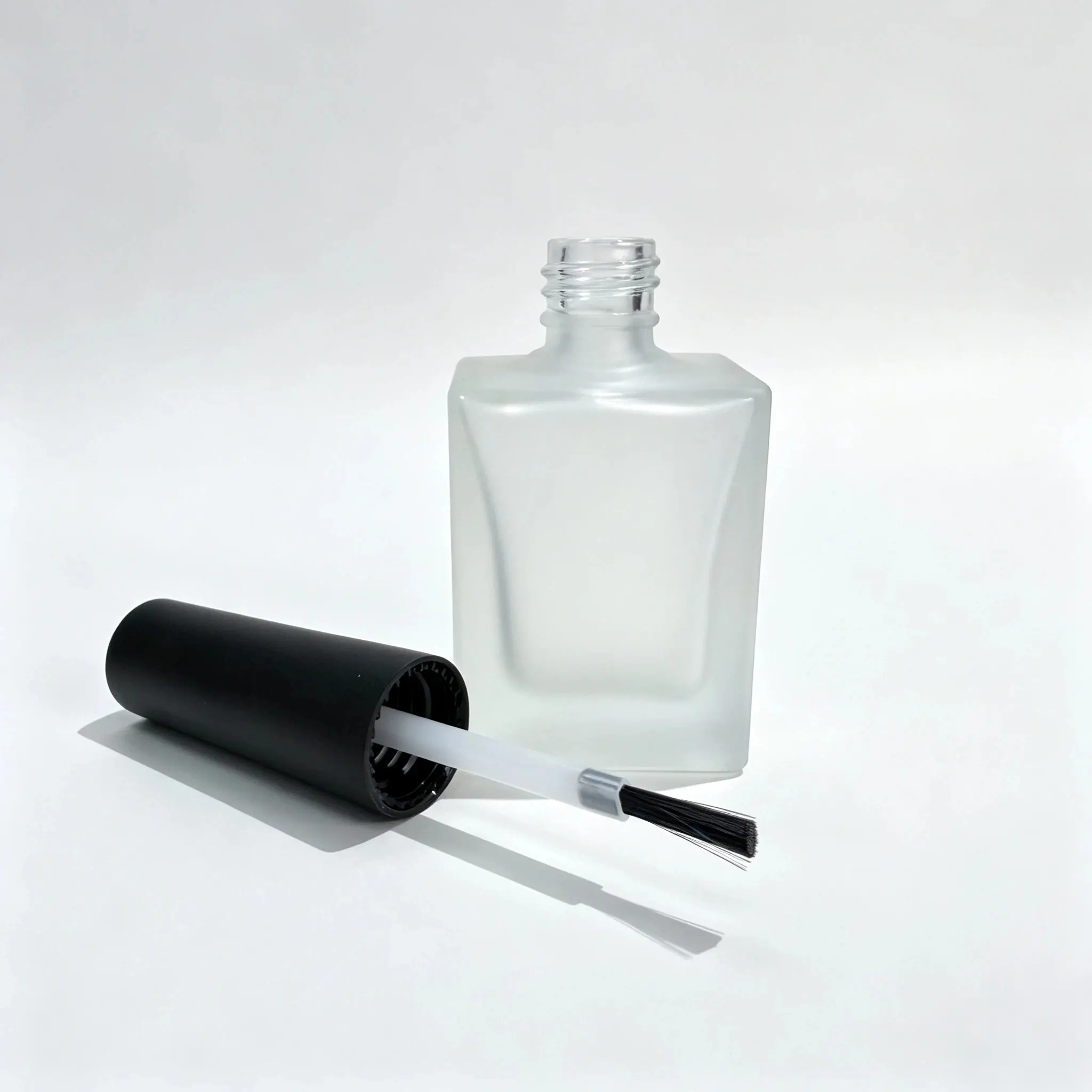15ml Frosted Square Nail Polish Bottle with Cap and Brush 15ml square frosted nail polish bottle displayed with its separate cap and nail polish applicator brush.