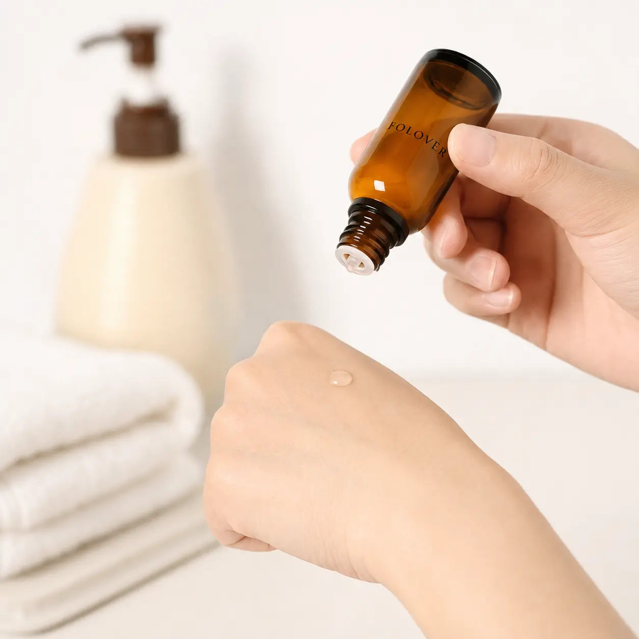30ml amber Euro dropper essential oil bottle shown dispensing liquid onto a hand in an application scene