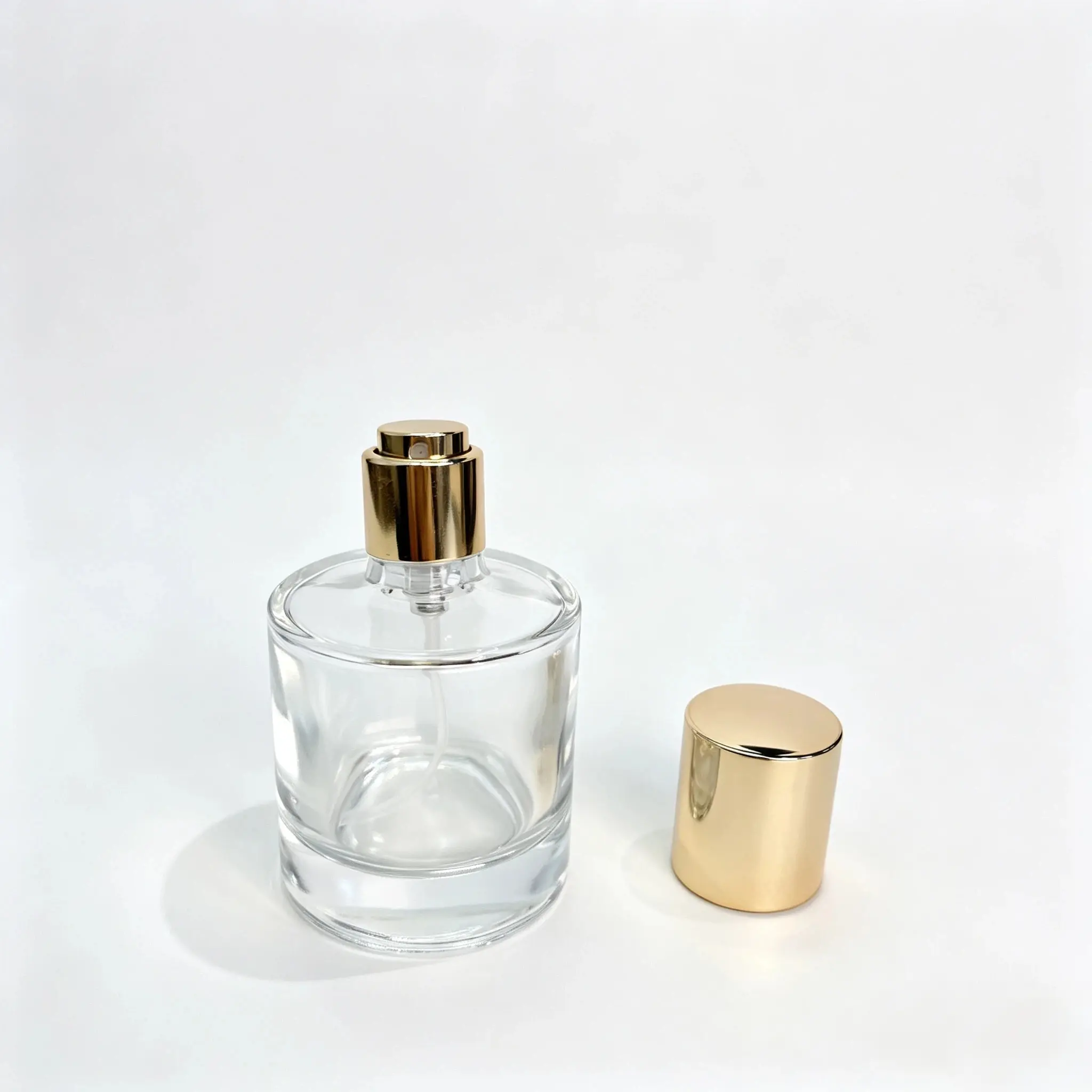 30ml cylindrical glass perfume bottle shown bare with the gold outer cap positioned separately beside the bottle
