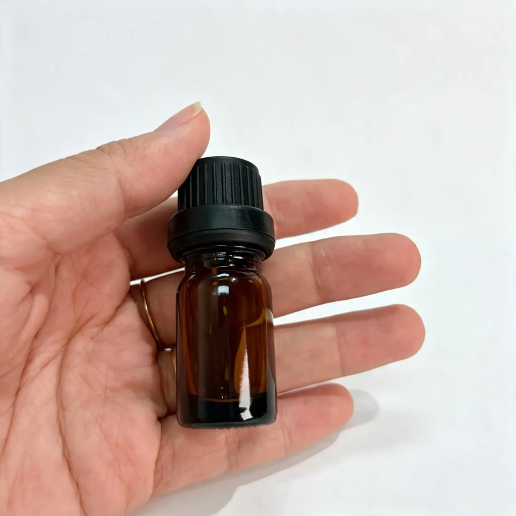 Compact 5ml Euro dropper essential oil bottle held in one hand to show its small packaging size