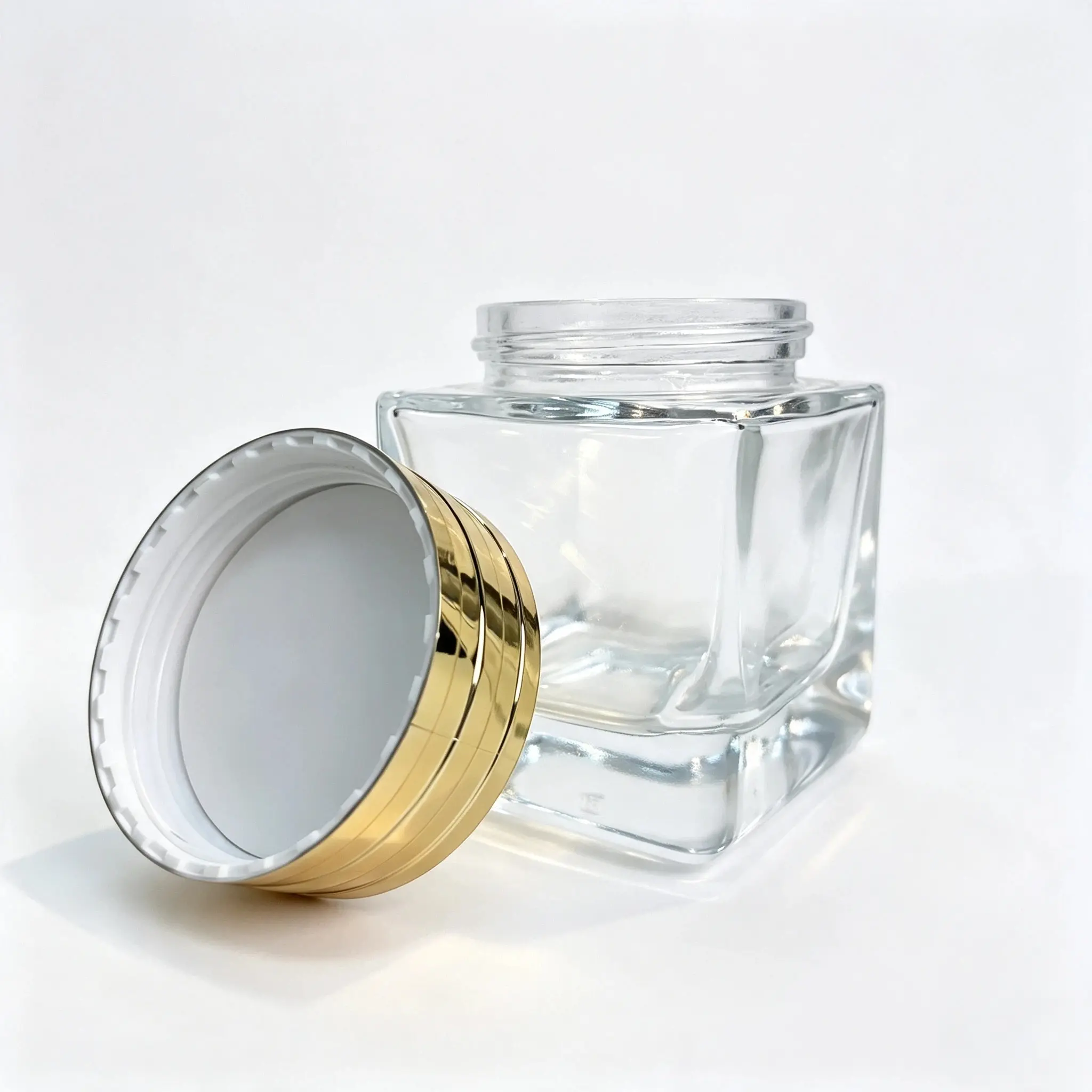 60g Square Glass Cream Jar with Gold Cap 60g square glass cream jar displayed together with its separate gold-colored cosmetic jar cap
