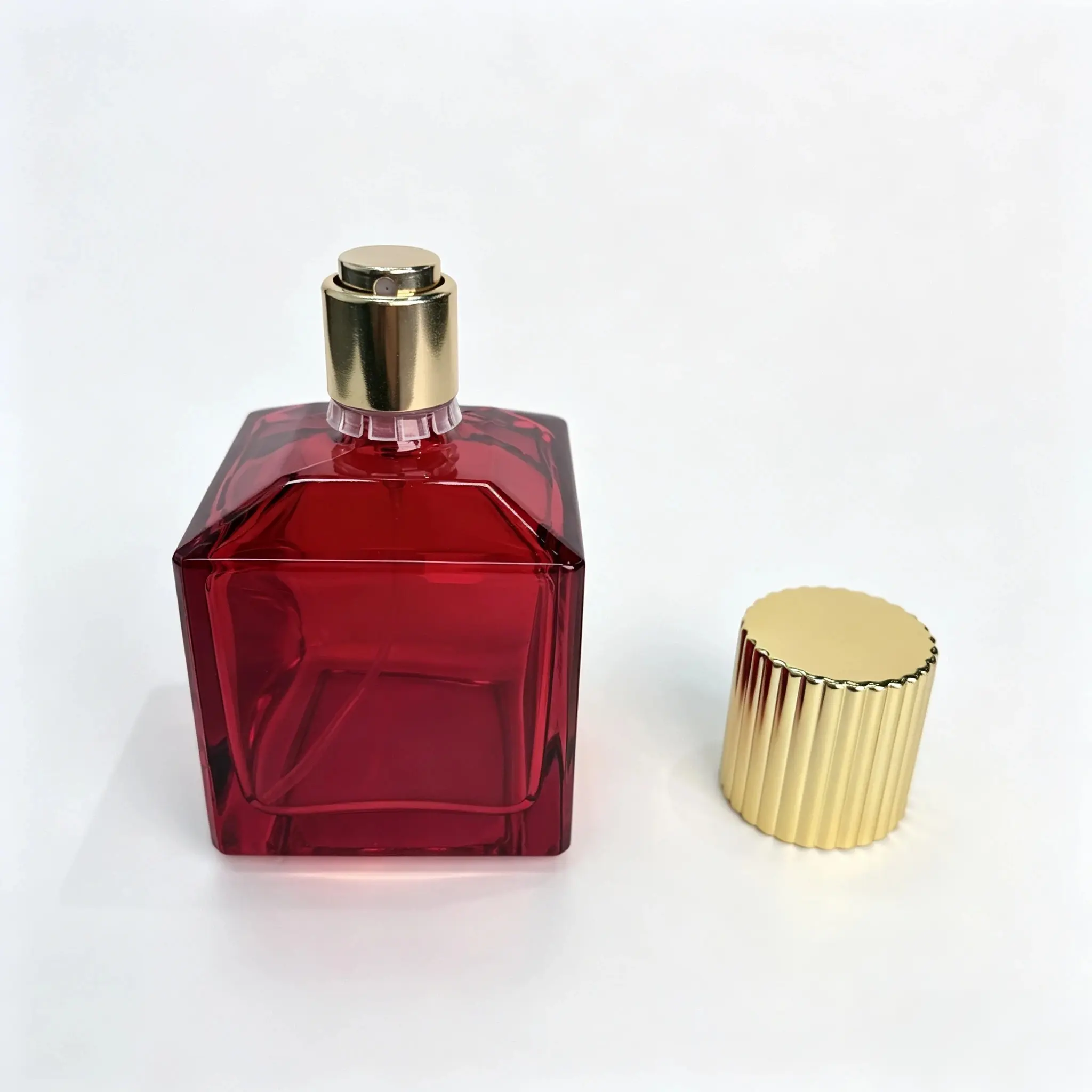 70ml red square glass perfume bottle shown bare with the gold striped outer cap standing separately beside the bottle