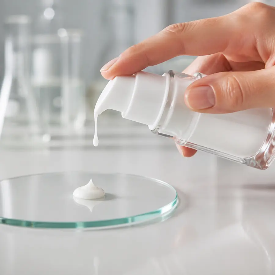 Cosmetic pump being pressed to dispense product from a glass bottle
