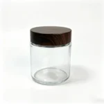 Vista frontal de um boião de creme em vidro transparente 100g com tampa de rosca com efeito madeira, para embalagem de creme facial e cuidados da pele.
