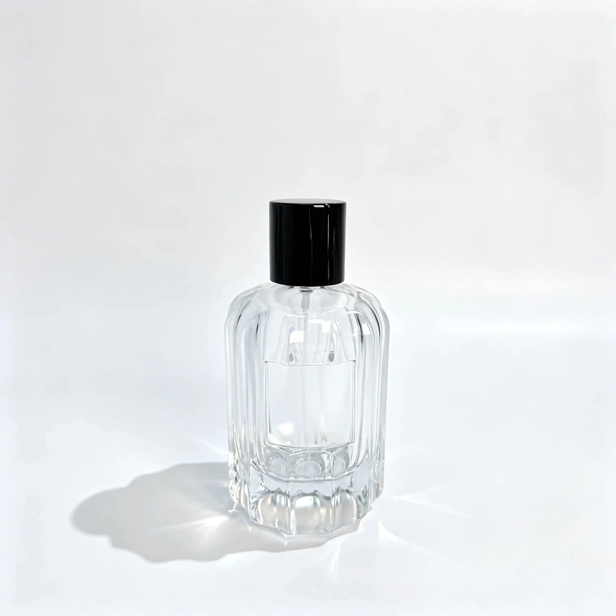 100ml Pahlı Nervürlü Parfüm Şişesi Önden Görünüm Monte edilmiş 100ml pahlı fitilli parfüm şişesinin dikey dokulu gövdesini, köşeli kenarlarını ve uyumlu kapağını gösteren önden görünüm.