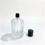 100ml chamfered ribbed perfume bottle standing without its cap, with the removed cap positioned beside the bottle to show the separate components.
