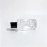Uncapped 100ml cylindrical perfume bottle lying horizontally to display its elongated body profile and vertical ribbed exterior from a different angle.