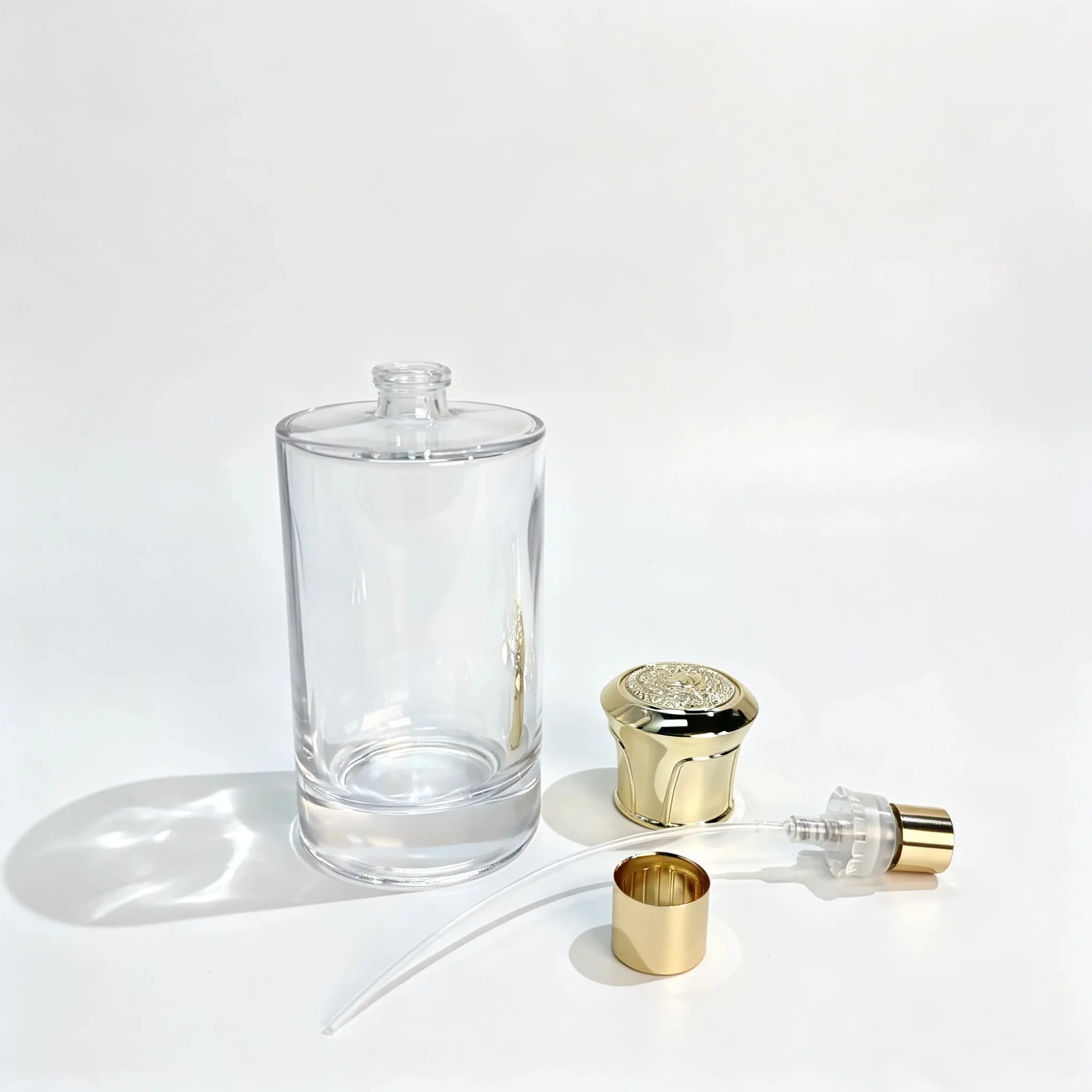 100ml زجاجة عطر أسطوانية مع غطاء بخاخ وأنبوب غطاس زجاجة عطر أسطوانية 100ml معروضة مع غطائها التاجي الذهبي وبخاخ العطر وأنبوب الغطاس مرتبة بشكل منفصل بجانب الزجاجة بدون غطاء.