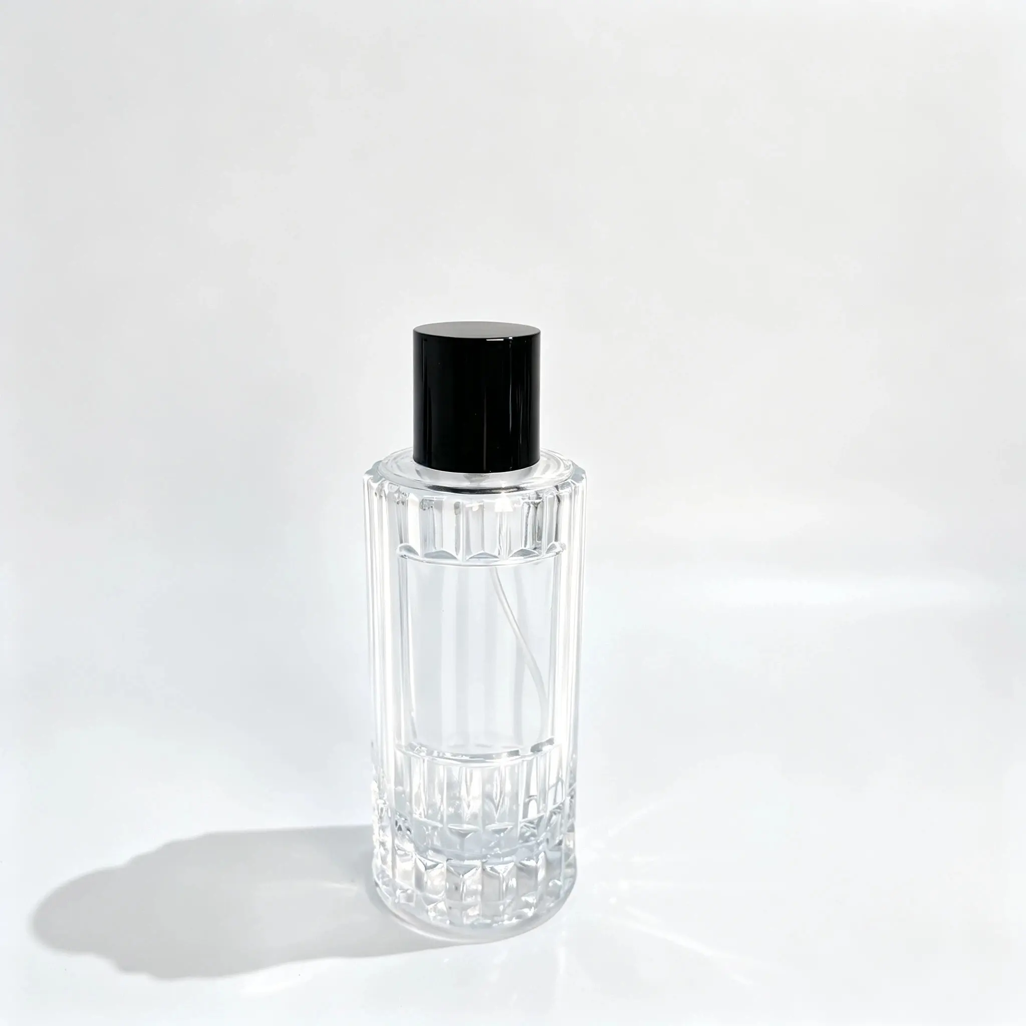 100ml Flacon de parfum colonne cannelée, vue de face Vue de face du flacon de parfum à colonne cannelée 100ml montrant son corps à nervures verticales, son pulvérisateur de parfum et son bouchon ajusté.