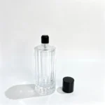 100ml fluted column perfume bottle displayed with its removable cap placed beside the bottle, showing the uncapped bottle profile and separate closure.