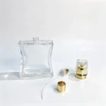 100ml curved waist perfume bottle with separate fragrance sprayer, dip tube, and cap components arranged beside the bottle for packaging assembly evaluation.