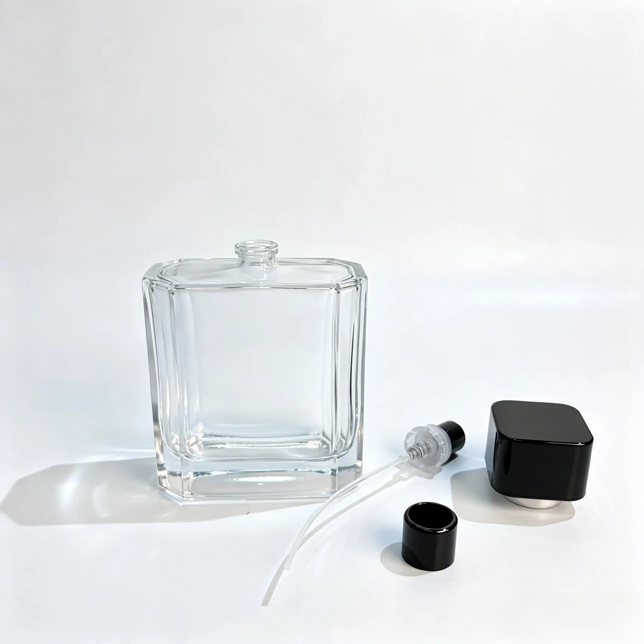 ขวดน้ำหอมแก้วลายริ้ว 100ml จัดแสดงคู่กับหัวสเปรย์น้ำหอม หลอดดูด และชิ้นส่วนฝาตกแต่งที่แยกออกจากกัน เพื่อเป็นข้อมูลอ้างอิงการประกอบบรรจุภัณฑ์.