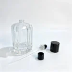 Uncapped 100ml chamfered ribbed perfume bottle with the fragrance sprayer, dip tube, and cap displayed separately beside the bottle body.