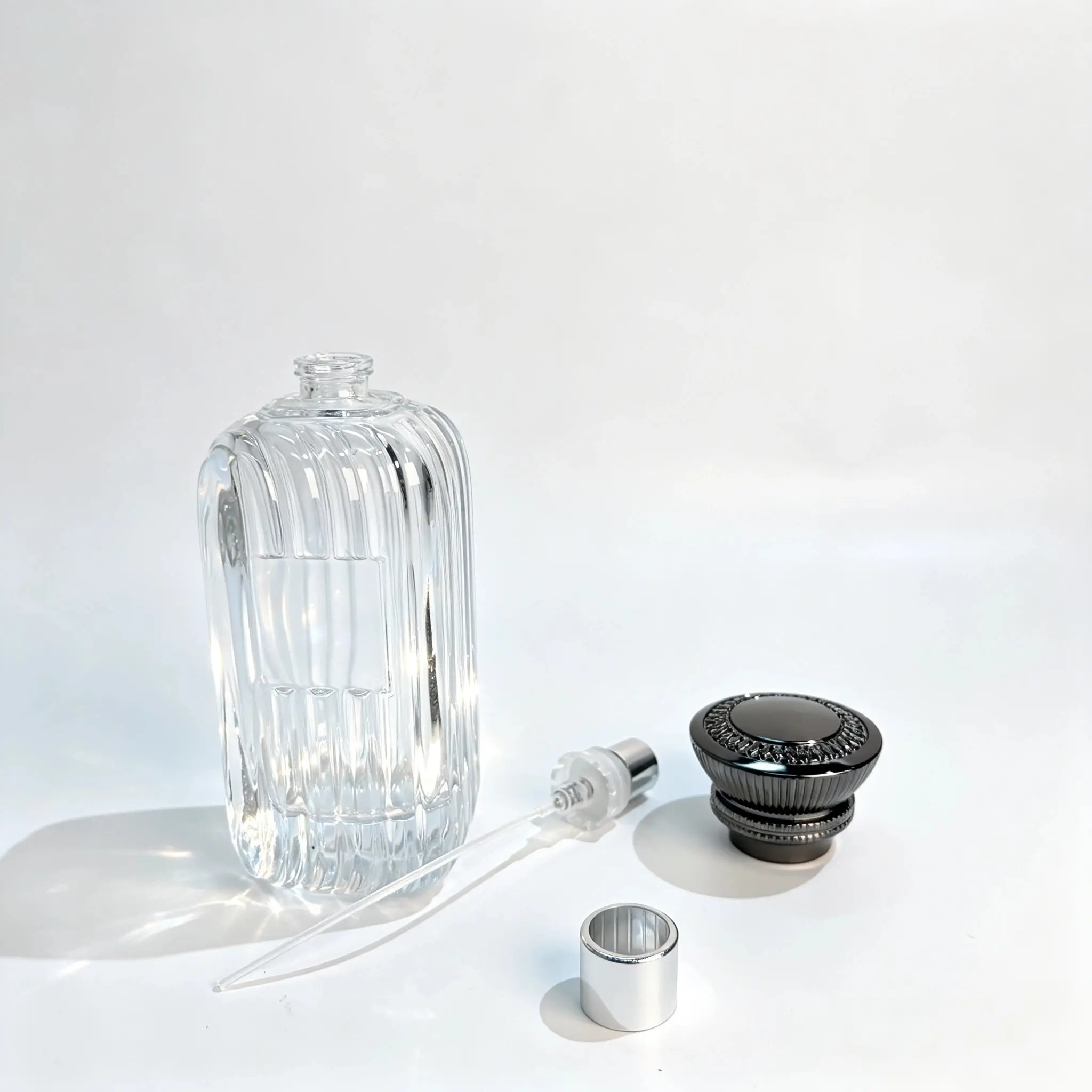 100ml Ribbed Perfume Bottle – Sprayer, Dip Tube and Crown Cap Components 100ml ribbed perfume bottle displayed with its separate perfume sprayer, dip tube, and embossed black crown cap for component selection.