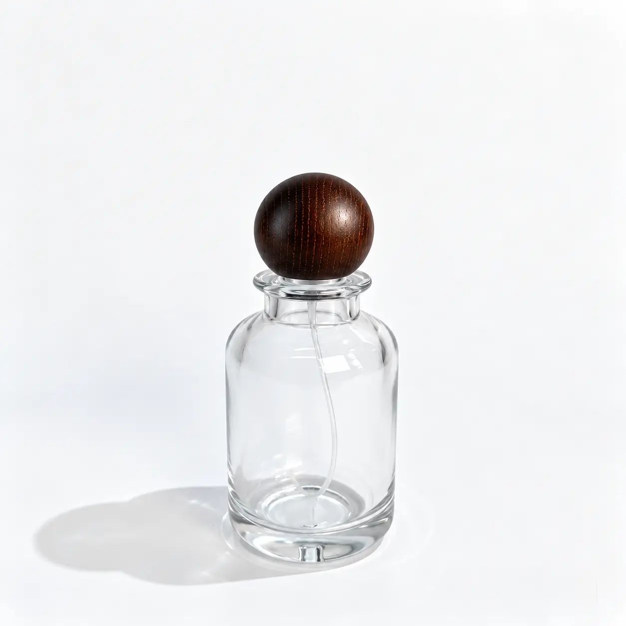 100ml yuvarlak parfüm şişesinin ön görünümü; şişkin gövdesi ve takılı ahşap top kapağı görülüyor.