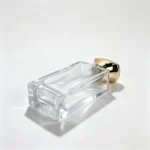 Side-lying 100ml rectangular perfume bottle with its bottom facing the viewer, highlighting the thick glass base and rectangular bottle profile.