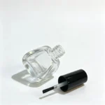 14ml frasco de vidro para verniz de unhas apresentado com a tampa preta e os componentes do pincel de verniz de unhas ao lado do frasco