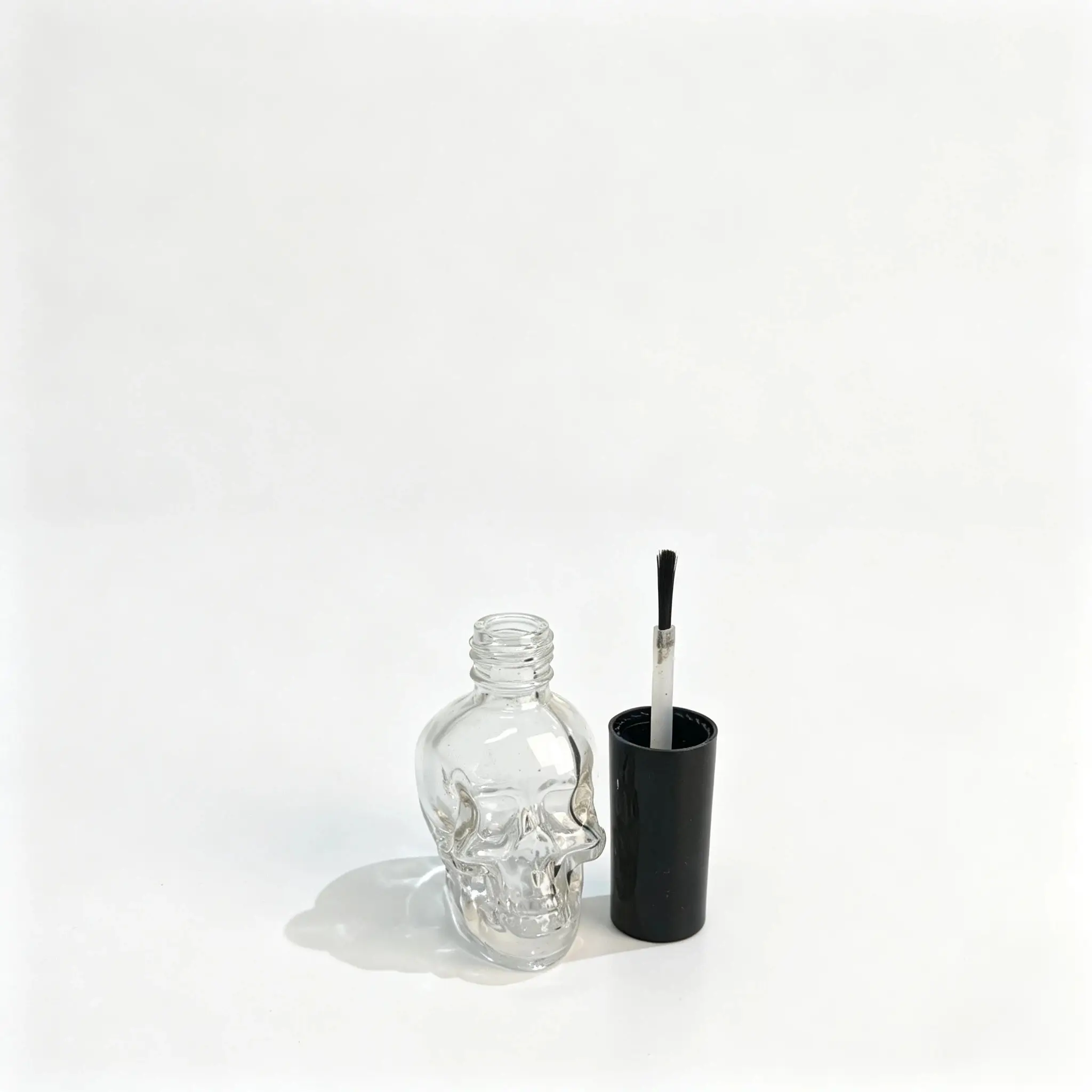 15ml Sticlă de ojă din sticlă în formă de craniu – Set capac și pensulă Sticlă de ojă din sticlă în formă de craniu 15ml prezentată cu capacul separat și pensula aplicatoare de ojă pentru evaluarea componentelor.