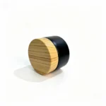 Side view of the 30g black glass cream jar showing its compact glass body and bamboo screw lid profile for facial cream packaging.