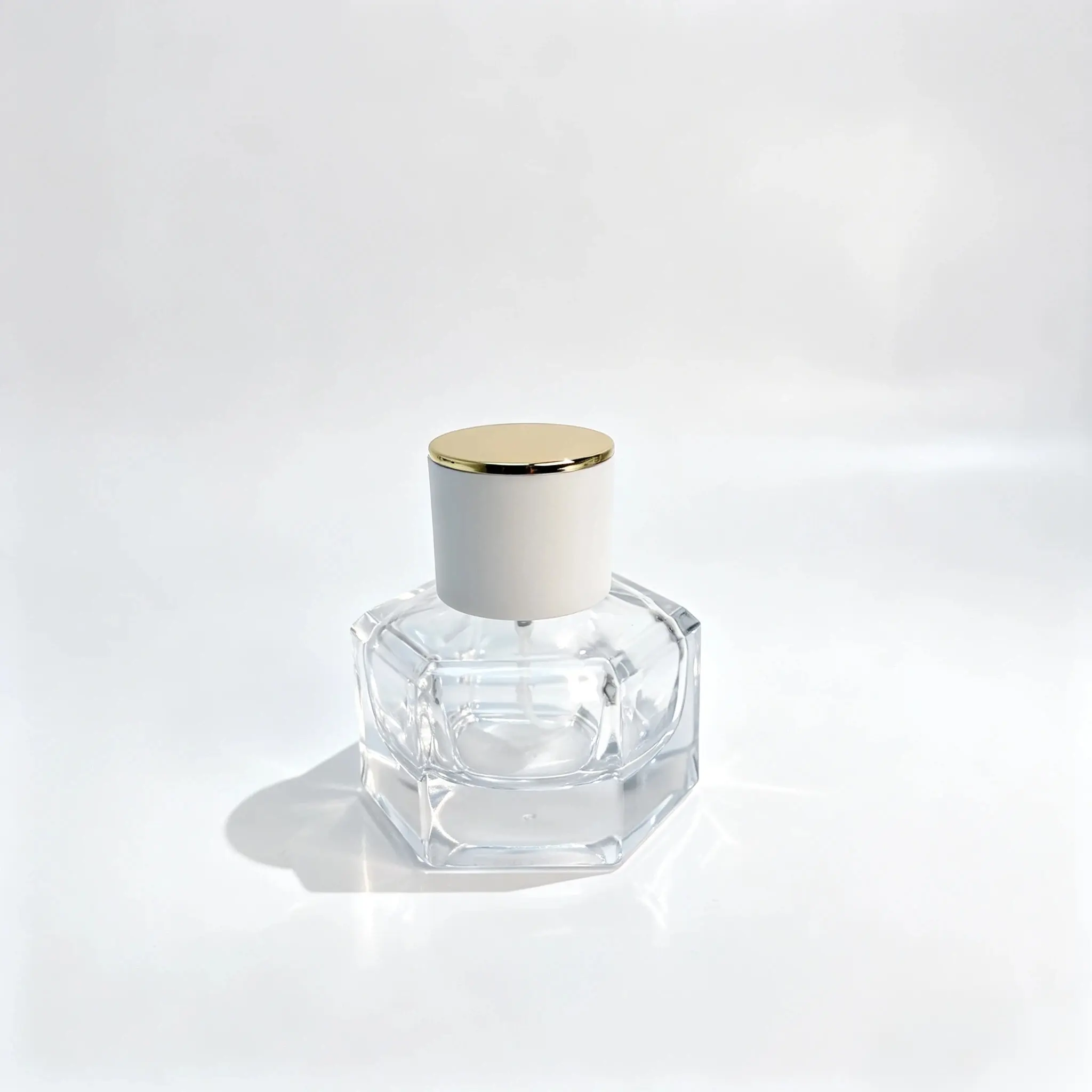 30ml زجاجة عطر زجاجية سداسية بغطاء أبيض وذهبي – منظر أمامي منظر أمامي لـ 30ml زجاجة عطر زجاجية سداسية تتميز بجسم هندسي سميك وغطاء أسطواني أبيض بقمة ذهبية اللون.