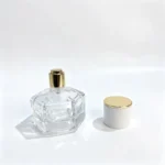 30ml hexagonal-cut glass perfume bottle with its white cylindrical cap and gold-colored top removed and placed beside the bottle.