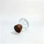 Side-lying view of the 30ml perfume bottle showing the rounded profile of its hemispherical wooden cap and assembled bottle design.separate closure and bottle profile.