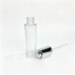 30ml round glass serum bottle displayed without its assembled closure alongside separate cosmetic packaging accessories