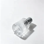 Side-lying 30ml vertical ribbed perfume bottle showing its bottom profile and the vertically textured cylindrical bottle body.