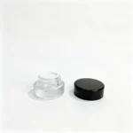 Clear glass cream jar and matching black screw cap displayed together for a compact 3g cosmetic sample packaging configuration.