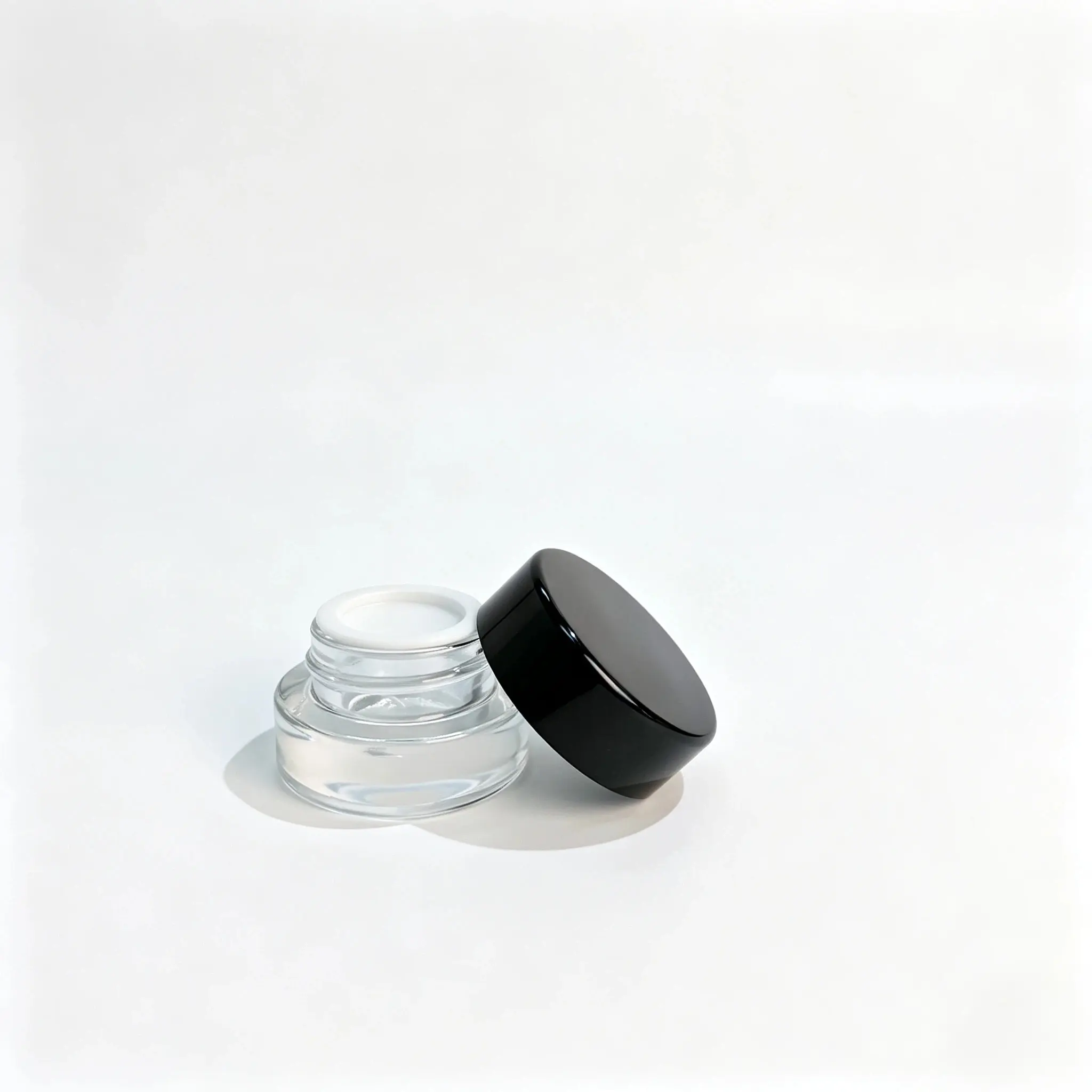 3g frasco de amostra de creme em vidro transparente apresentado com a sua tampa de rosca preta e o componente separado de tampa com aba de puxar, como referência para a montagem da embalagem cosmética.