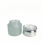 50g frosted glass cream jar displayed with its matching silver screw cap, showing the glass container and closure for cosmetic packaging.