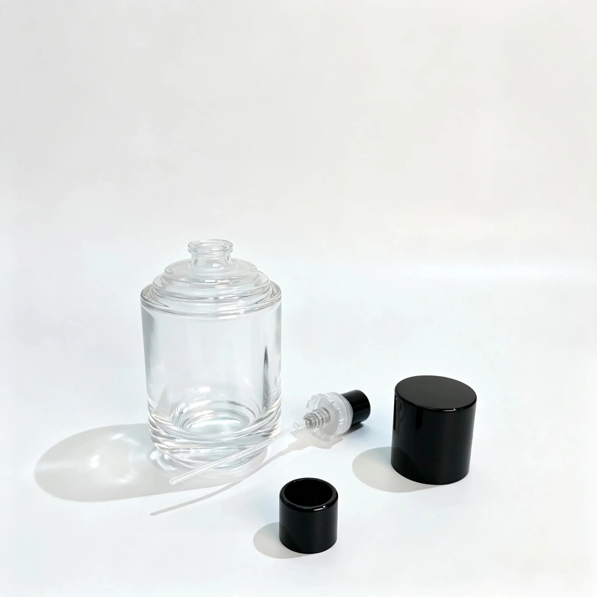 50ml Silindirik Parfüm Şişesi - Sprey ve Kapak Bileşenleri Kapağı çıkarılmış 50ml silindirik parfüm şişesi, ayrı parfüm spreyi, dip tüpü ve dekoratif kapak bileşenlerinin yanında sergilenmektedir.