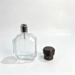 The 50ml octagonal perfume bottle displayed with its black coil-design cap removed and placed beside the bottle, showing the exposed spray pump.