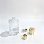 Uncapped 50ml petal fluted perfume bottle displayed alongside its separate fragrance sprayer, dip tube, and decorative cap components.