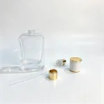 Uncapped 50ml rectangular perfume bottle displayed with separate perfume sprayer, dip tube, and white cap with gold trim for component evaluation.