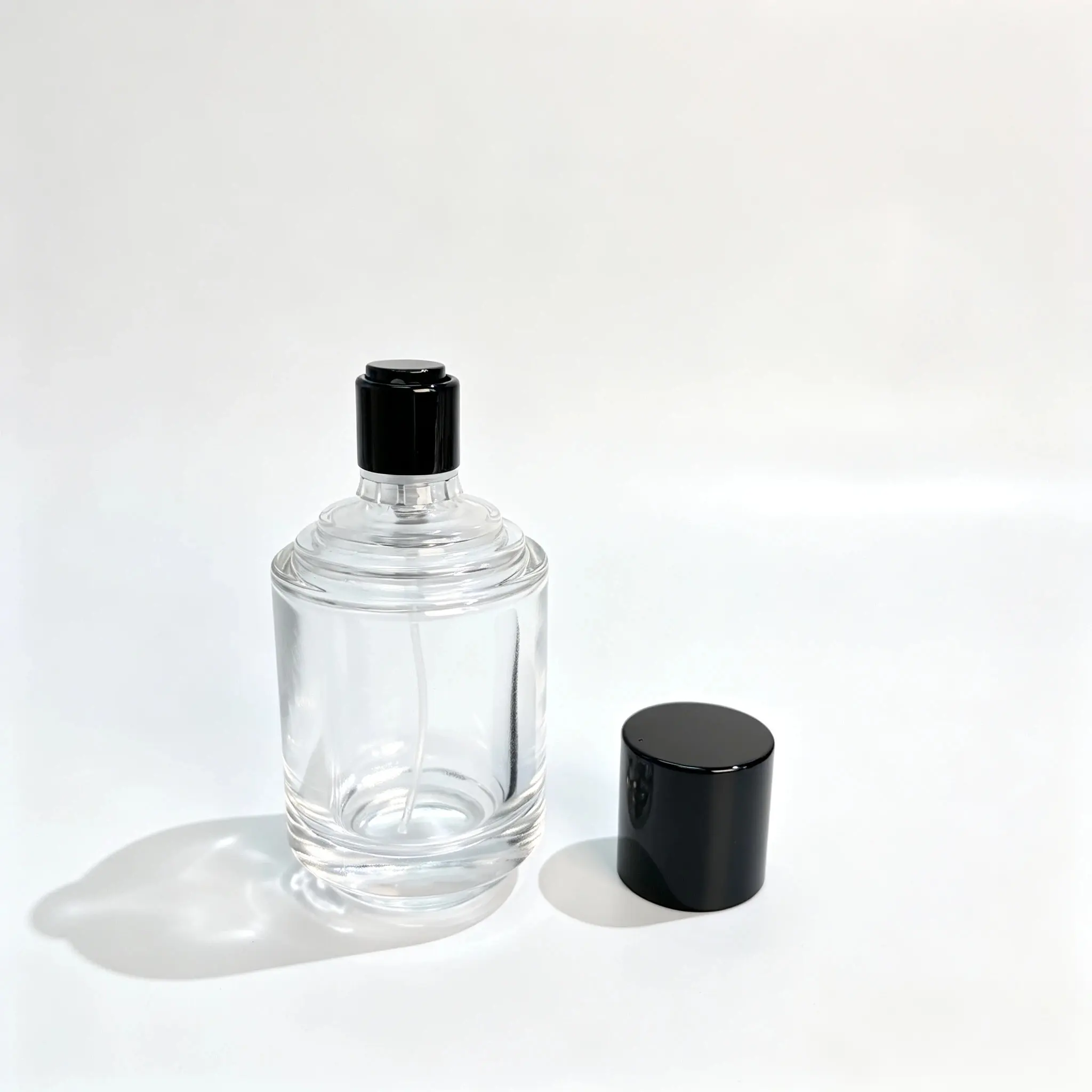 50ml Kademeli Boyunlu Parfüm Şişesi - Kapak Çıkarılmış Görünüm 50ml kademeli boyunlu silindirik parfüm şişesi; dekoratif kapağı çıkarılmış ve kapaksız ambalaj konfigürasyonunu göstermek üzere şişenin yanına yerleştirilmiştir.
