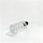 Side-lying view of the uncapped 80ml diamond-faceted perfume bottle showing its bottom structure and the geometric profile of the fragrance bottle body.
