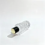 Side-lying view of the 80ml diamond-faceted perfume bottle positioned to show the cap end and the bottle's geometric exterior profile.