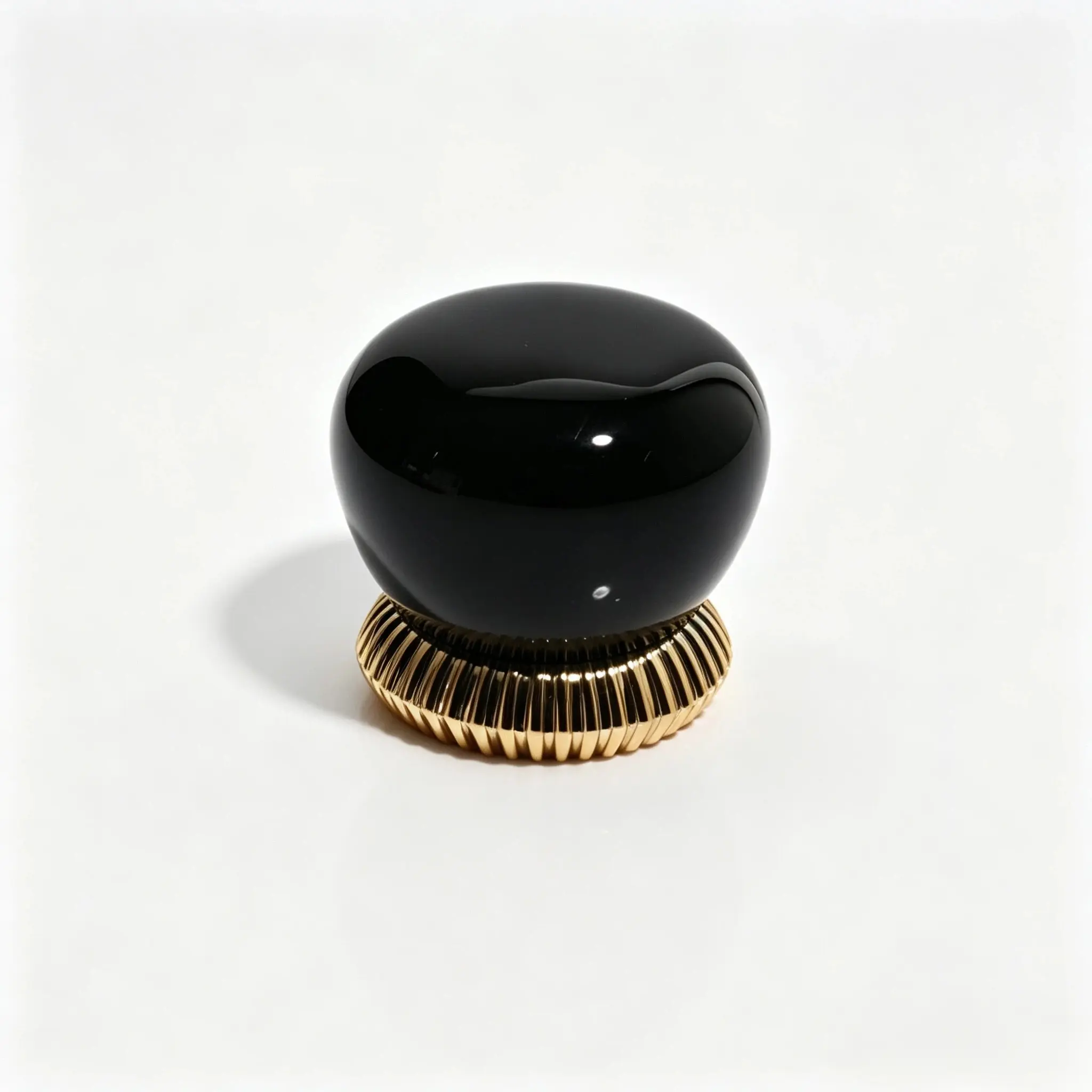 Capac de parfum din rășină negru, în formă de pietricică, prezentat din față, cu detalii cu nervuri verticale și un profil rotunjit neregulat