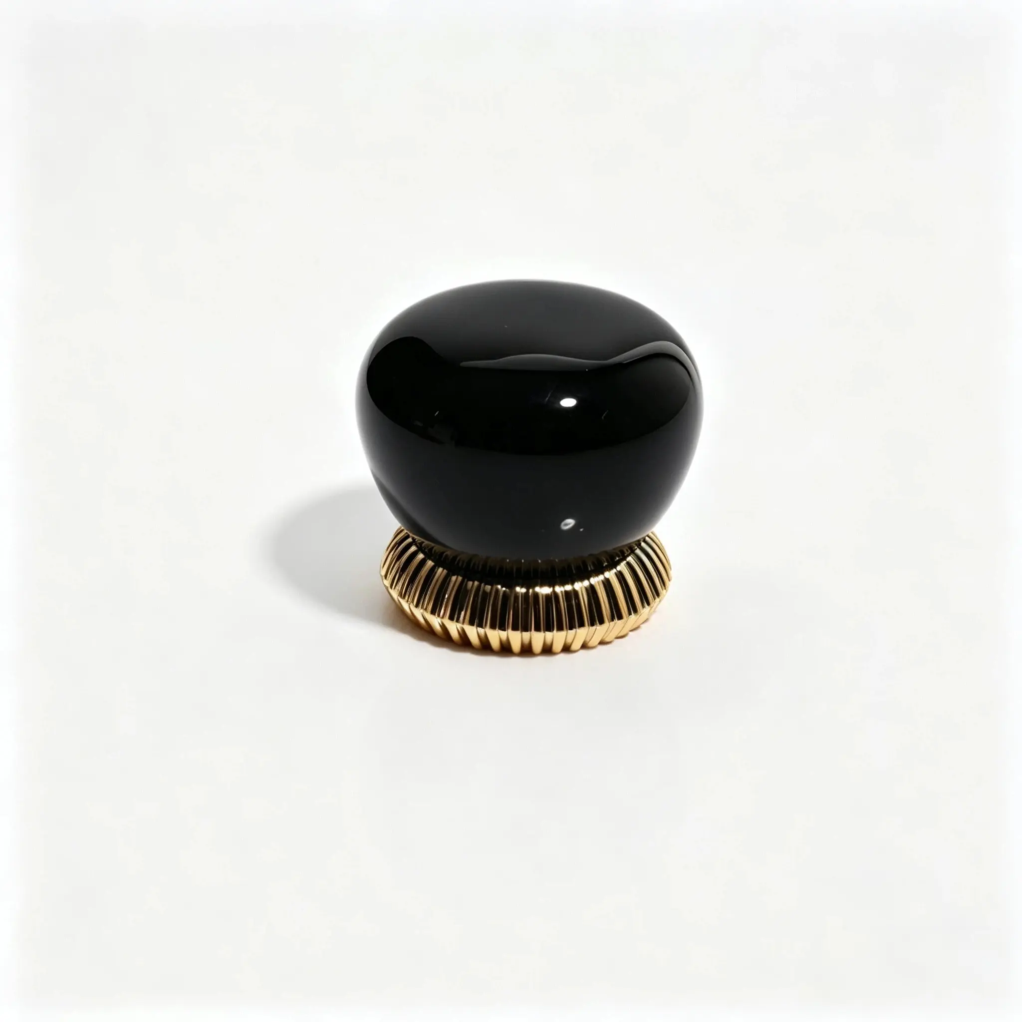 Capac de parfum din rășină negru prezentat din spate, cu forma sa inspirată de pietricică și suprafața texturată vertical vizibile
