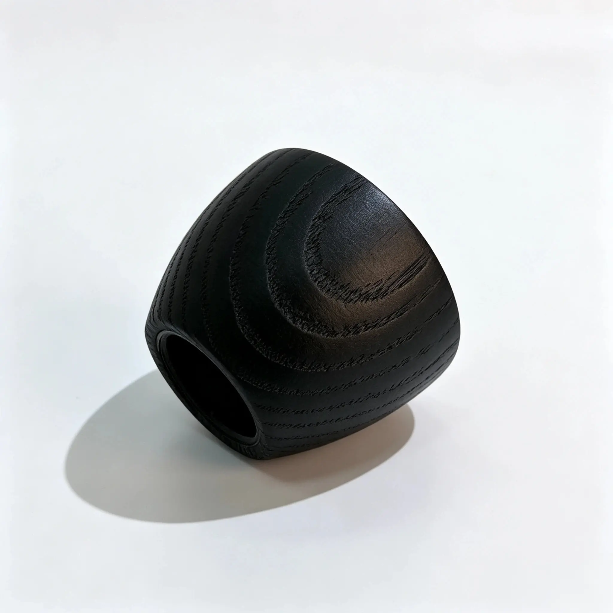 Black round wooden perfume cap positioned horizontally with the lower opening facing left and the circular profile visible