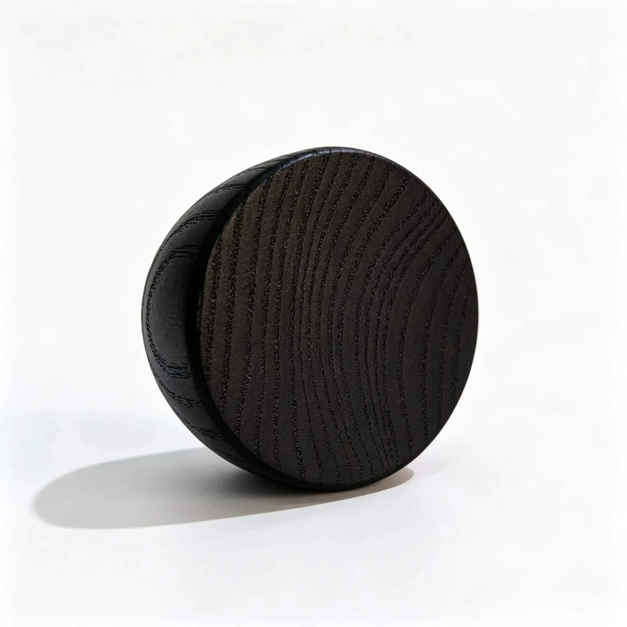 Black round wooden perfume cap shown from the rear with the dark cylindrical closure profile visible