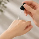 Black screw cap glass dropper in use with liquid dispensing through the transparent glass pipette