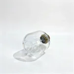 Short round perfume bottle positioned horizontally with its base facing the viewer, showing the thick-bottom design and cylindrical bottle body.