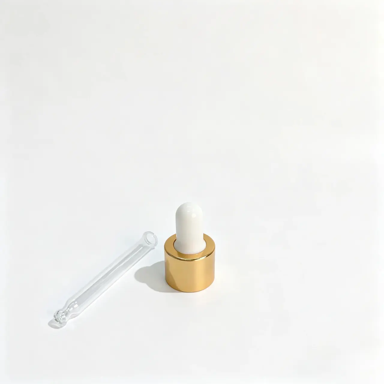 Composants de la pipette compte-gouttes à collerette en aluminium doré Composants du compte-gouttes à collerette en aluminium doré montrant la fermeture à poire en caoutchouc blanc et la pipette en verre transparent séparée