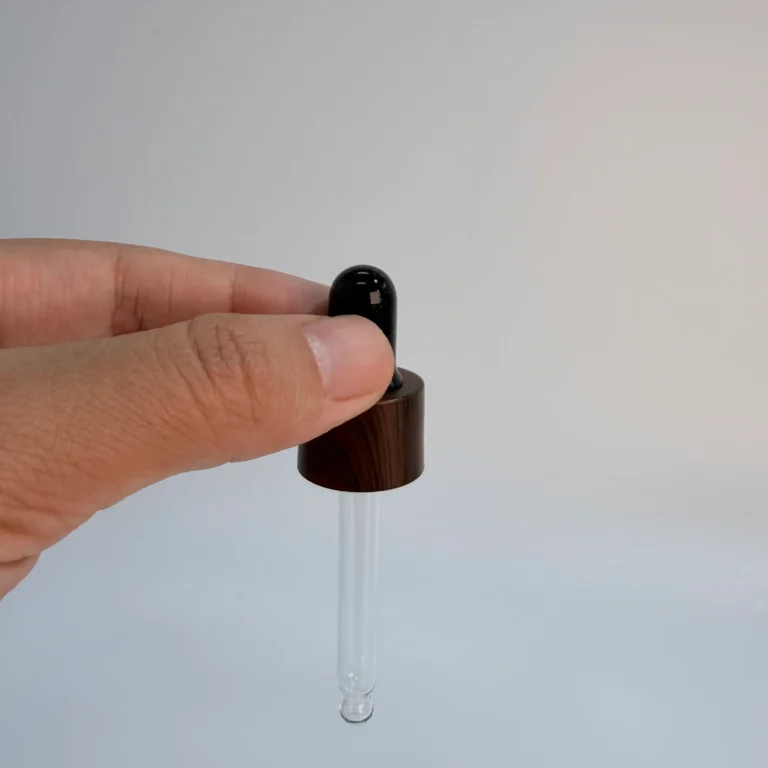 Wood grain aluminum collar glass dropper shown from the front with a black rubber bulb and transparent glass pipette