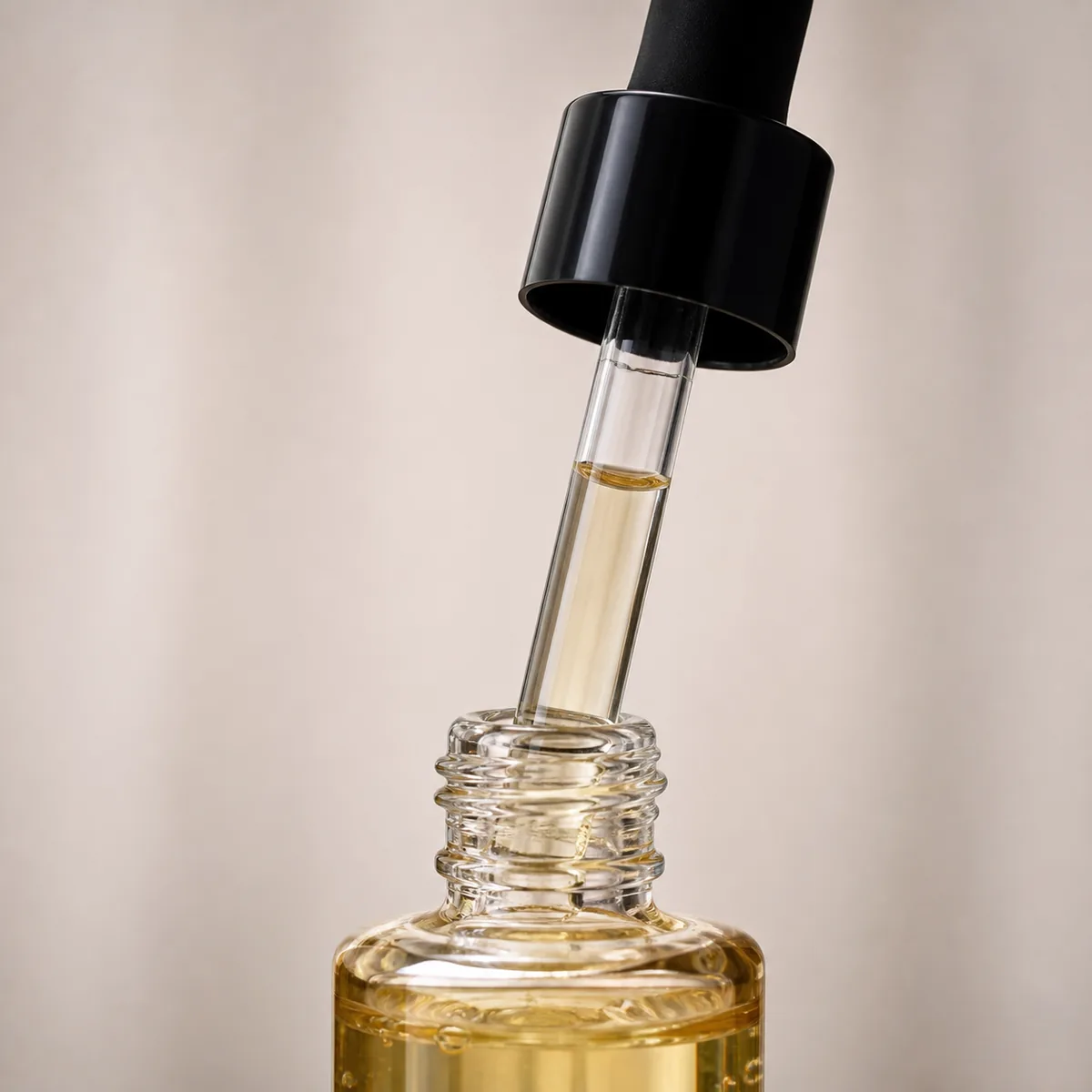 Glass dropper drawing a partial liquid column with a visible air space